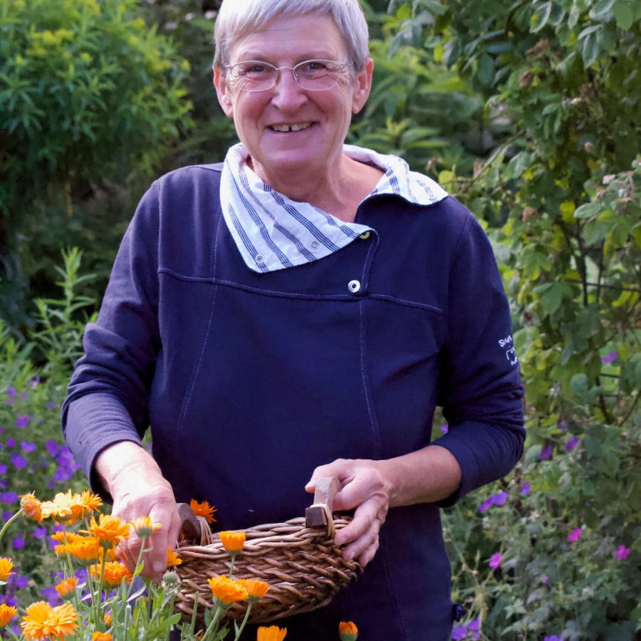 Brigitte Dammann im Garten mit Kräutern